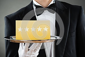 Midsection Of Waiter Holding Tray With Star Rating Label