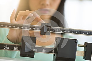 Midsection Of Woman Adjusting Weight Scale