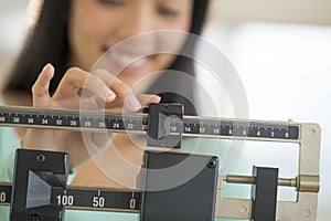 Midsection Of Woman Smiling While Adjusting Weight Scale