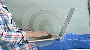 Midsection of woman using laptop lying on sofa