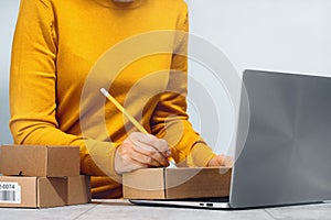 Midsection of a woman writing on a cardboard box. despatch