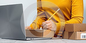 Midsection of a woman writing on a cardboard box. despatch