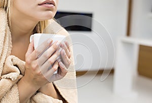 Midsection of young woman holding coffee mug in house