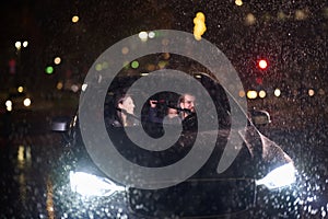 In the midst of a nighttime journey, a happy family enjoys playful moments inside a car as they travel through rainy