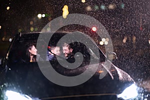 In the midst of a nighttime journey, a happy family enjoys playful moments inside a car as they travel through rainy