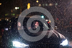 In the midst of a nighttime journey, a happy family enjoys playful moments inside a car as they travel through rainy