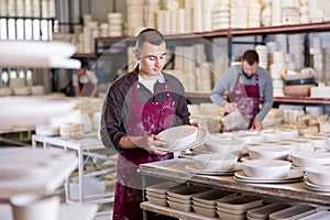 Ceramicist placing plates on storage racks in pottery studio photo