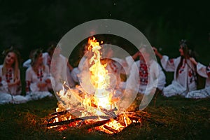 Midsummer night. Young people in Slavic clothes sitting near the bonfire