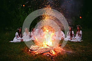 Midsummer night. Young people in Slavic clothes sitting near the bonfire