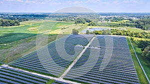 Midwest solar farm aerial of solar panels in rural area with farmland and nearby swamp