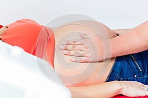 Midwife exanimating belly of pregnant woman manually