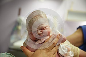 Midwife holding up a vernix covered newborn