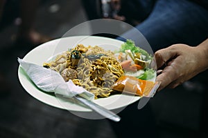 Mie Goreng served with chili sauce and cutlery from street night market in Jakarta, Indonesia