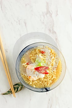 Mie Kuah Telur for Sahur in Ramadan, Instant Noodle Soup Served on Glass Bowl with Poached Egg and Chili