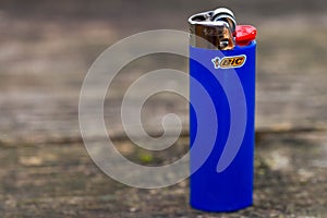 Blue Bic cigarette lighter on aged pine wood boards, space for text.