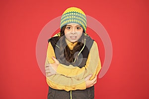 It might be too cold to trek outside. Little child feel cold red background. Small girl shiver in cold weather wear