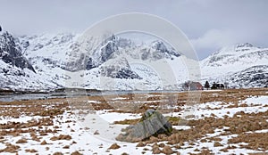 Mighty mountains and tiny Red and Blue House on the Lofoten in Norway in winter