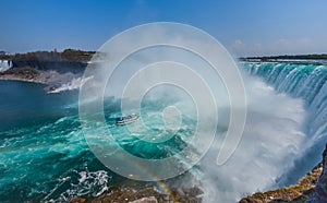 Mighty Niagara River roars over the edge of the horseshoe falls in Niagara Falls Ontario. Misty foggy spray rises up.