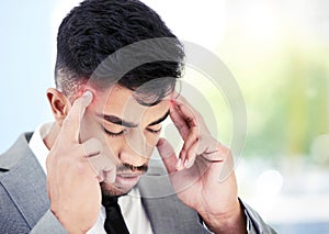 This migraine is causing me to miss out on work. a young businessman experiencing a headache while working in an office.