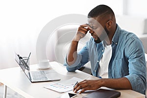 Migraine Concept. Overworked African American Man Suffering From Headache At Workplace