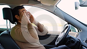 A migraine like headache torments the driver behind the wheel, holds his head with his hands,