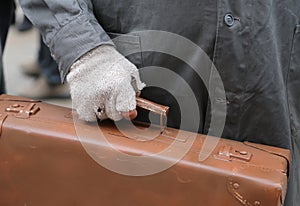 migrant with old leather suitcase and the broken glove