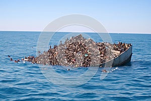Migrants in an overcrowded boat cross the sea photo