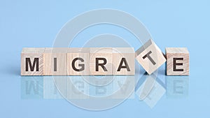 migrate word is made of wooden building blocks lying on the yellow table, concept photo