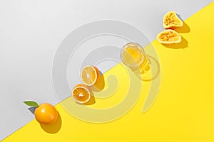 Miinimal orange juice flat lay. Fresh orange and glass of juice on trendy colors gray and yellow background. . Creative breakfast