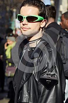 Man with black leather trench coat, Prada mini bag and green Balenciaga sunglasses before Dolce