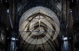 Statue of crucified Jesus Christ inside Milan Cathedral. Holy cross in interior of dark Catholic church, view of crucifix in altar