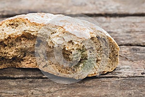 Mildew on a slice of bread, lying on a wooden surface. Stale bread, covered with mildew_