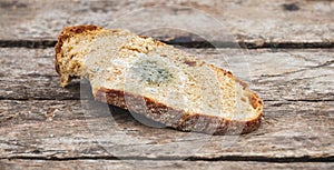 Mildew on a slice of bread, lying on a wooden surface. Stale bread, covered with mildew_