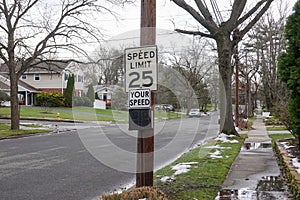 A 25 mile per hour speed limit sign on a wooden utility pole on the side of a community street