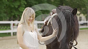 Milennial woman and horse at horse club stroking the horse and smiling at him