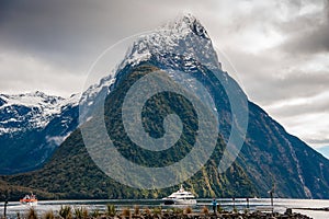 Milford Sound and Mitre Peak, South Island, New Zealand. Steep sided mountains rise from calm waters of the fiord with moody sky