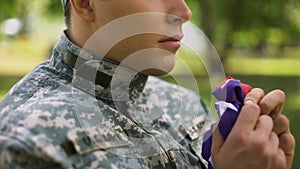 Military agent holding american flag, praying for country, war memories, faith