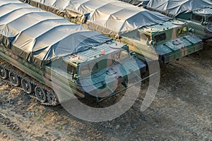 Military amphibious cargo vehicles parked on a battlefield