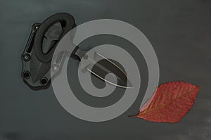 Military autumn. Autumn leaf and black knife on a black background. Diagonal composition.