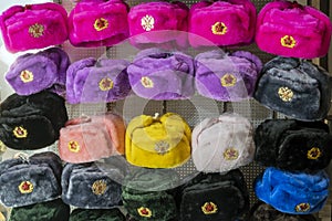 Military caps of different colors with the coats of arms of Russia and the USSR as Souvenirs from Moscow. Rows of russian winter