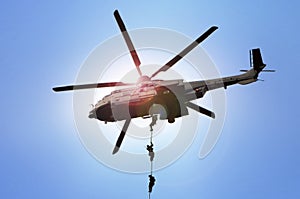 Military commando helicopter drops under bright daylight