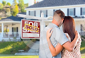 Military Couple Looking At House with Sold For Sale Realty Sign