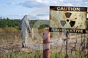 Military dosimetrist measures the radiation area, a sign with the inscription: caution, radiation, chemical protective suit and ga