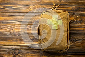 Military first aid kit on a brown wooden background.
