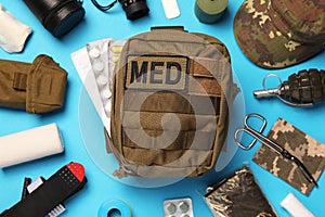 Military first aid kit and equipment on light blue background, flat lay