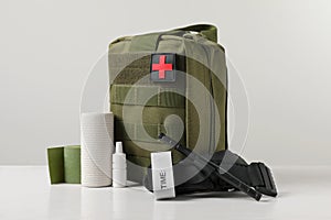 Military first aid kit, tourniquet, drops and elastic bandage on white table