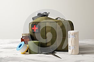 Military first aid kit, tourniquet, pills and elastic bandage on light grey table