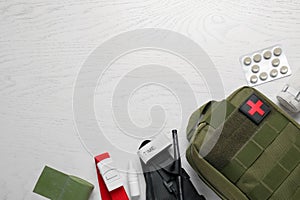 Military first aid kit, tourniquet, pills and elastic bandage on white wooden table, flat lay. Space for text