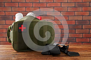 Military first aid kit and tourniquet on wooden table