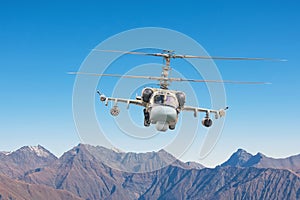 Military helicopter with armament flies on tops of mountains